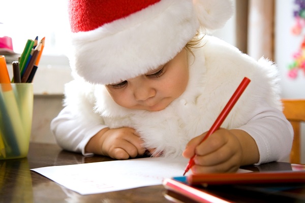 photo d'un enfant qui écrit une lettre au père noël pour demander des jouets